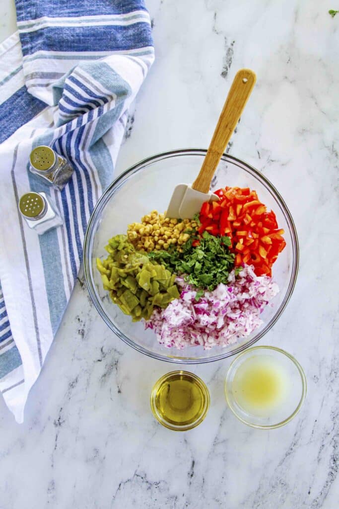 all food ingredients in a mixing bowl with dressing ingredients on the side