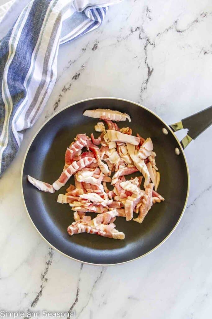 cut pieces of uncooked bacon in a skillet