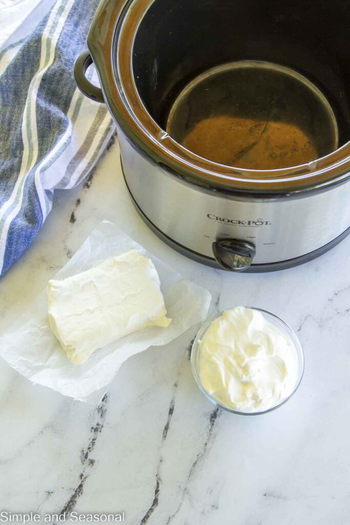 cream cheese and sour cream next to a slow cooker