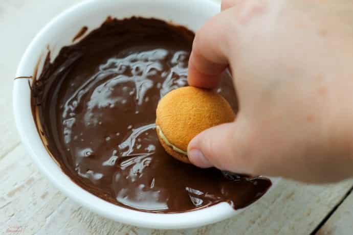 hand dipping cookie top in chocolate