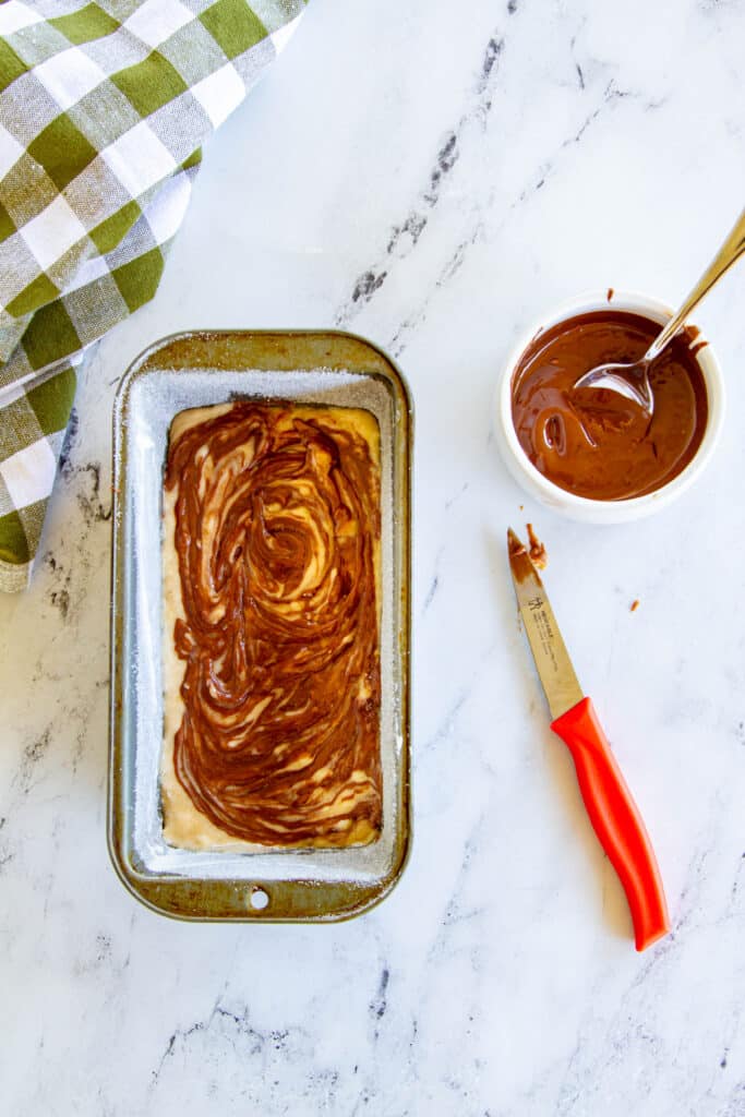 nutella swirled into batter in loaf pan with small knife