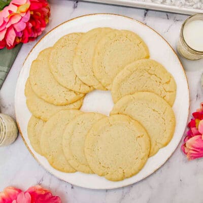 golden baked sugar cookies on a white plate with gold edging