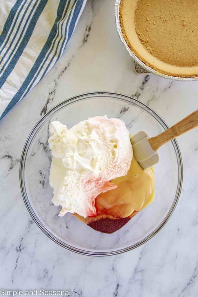 cool whip, condensed milk and kool-aid powder in a mixing bowl before stirring