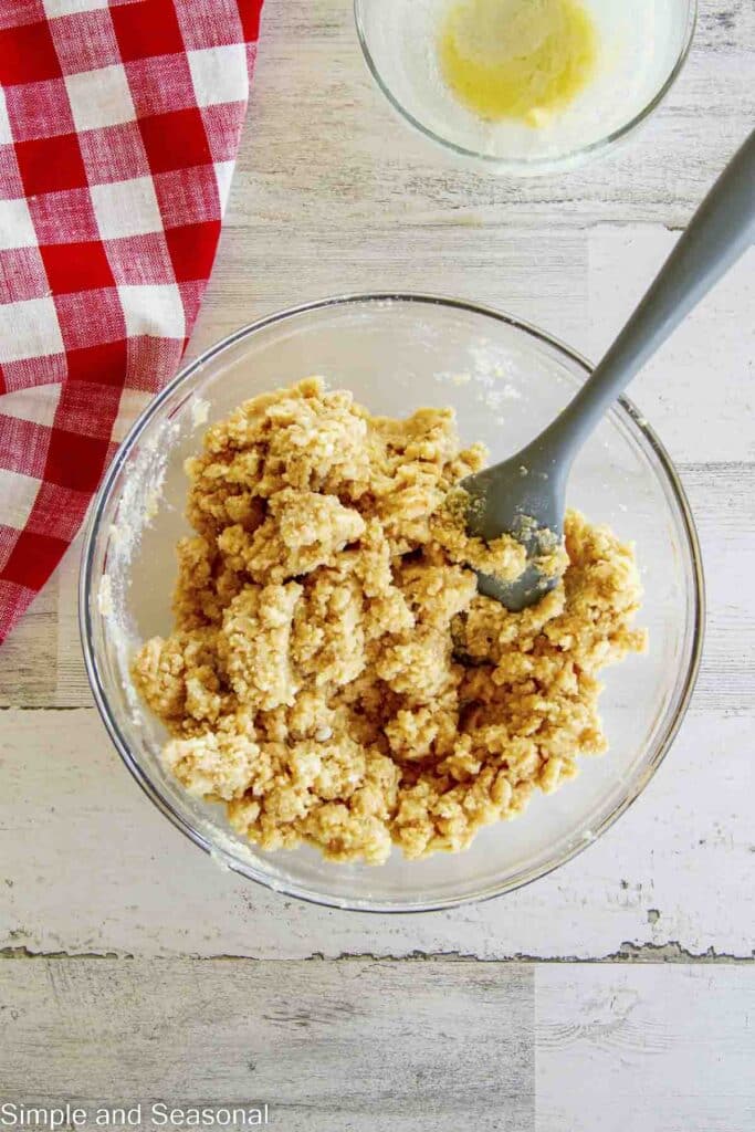 mixed butter and dry cookie bar ingredients in a bowl with spatula