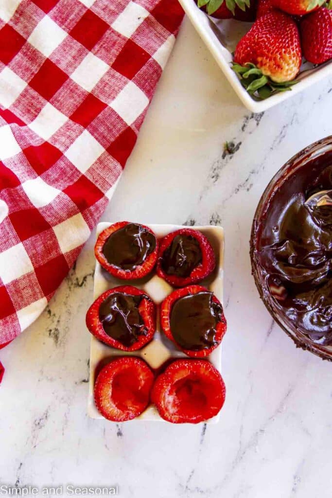 hulled strawberries in an egg carton with chocolate filling in some of them