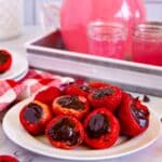white plate filled with strawberries stuffed with chocolate ganache and pink lemonade pitcher in the background