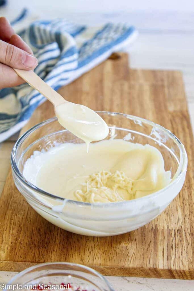 melted white chocolate on a spoon hovering over a bowl