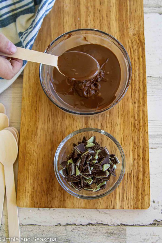 melted milk chocolate on a spoon with mint pieces in the background
