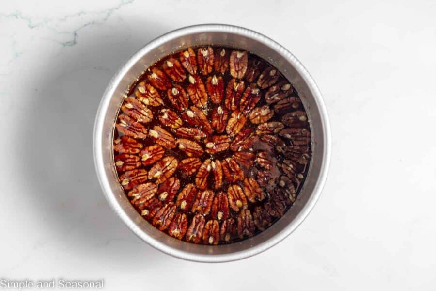 pecans neatly arranged in butter and sugar mixture