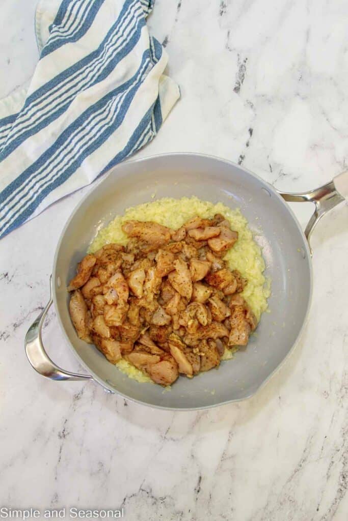 cooked onions and seasoned chicken in the skillet