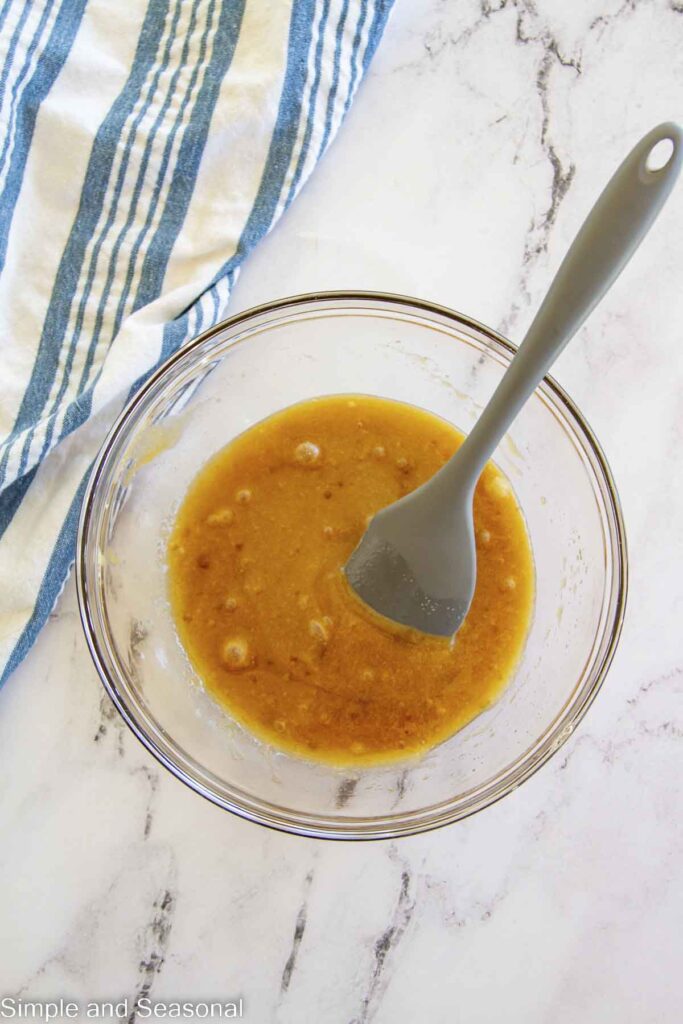 large spoon in mixing bowl with wet ingredients mixed together