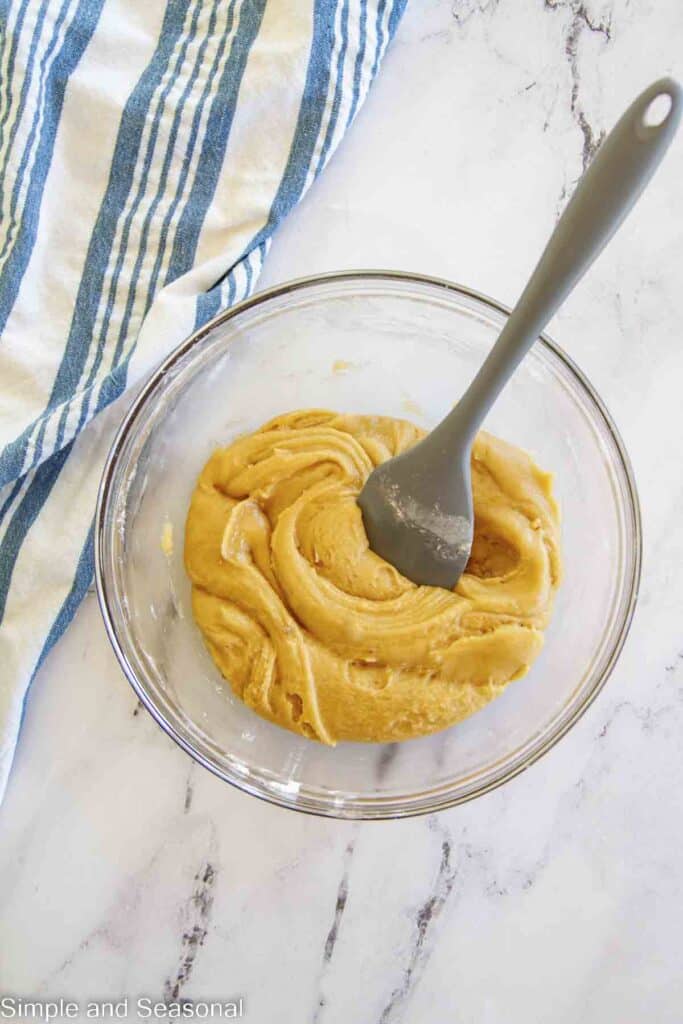 spoon mixing wet and dry together to create cookie dough